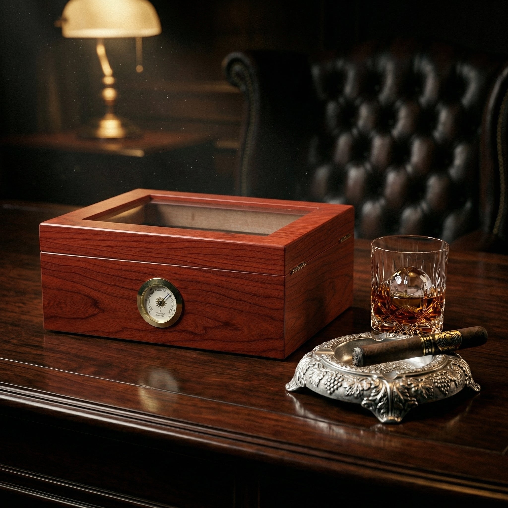 Open desktop cigar humidor with a classic deep mahogany wood finish and tempered glass lid. Interior shows the Spanish cedar wood tray, gold hinges, and a built-in humidifier. Features a traditional gold-rimmed analog hygrometer on the front.