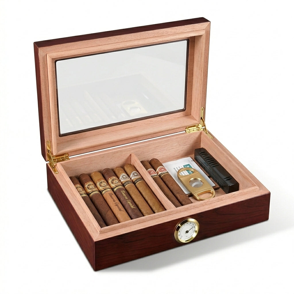 Open cherry wood cigar humidor isolated on white. Displays the Spanish cedar interior, adjustable divider, several premium cigars, a gold cigar cutter, and a black humidifier unit. Features an external analog hygrometer.